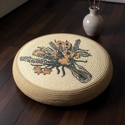 Round woven cushion with floral embroidery on a wooden floor