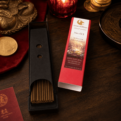 Incense stick holder with incense sticks and a box on a wooden surface.