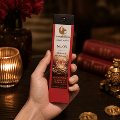 Hand holding a red innerbillion ritual series product packaging on a wooden surface with decorative items.
