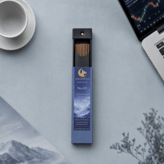 Incense stick packaging with a blue label on a light gray surface with a laptop and mug.