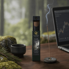 Incense stick with packaging on a wooden surface, laptop in the background