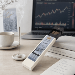 Incense stick with packaging on a desk next to a laptop and books