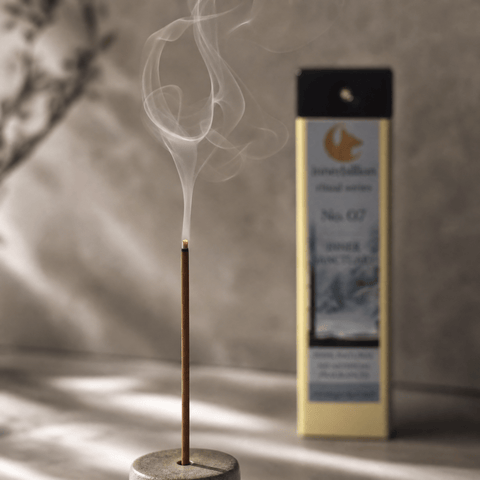 Incense stick with smoke and packaging in the background