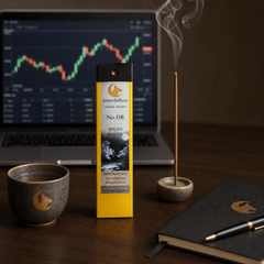 Incense stick with packaging on a desk next to a laptop displaying stock market graphs.