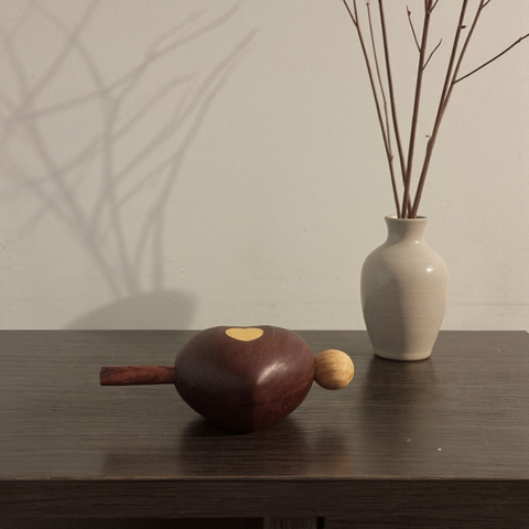 Decorative Wooden Fish resembling a chestnut and a vase with branches on a wooden surface.