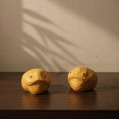 Two wooden toad-shaped objects on a wooden surface with a neutral background